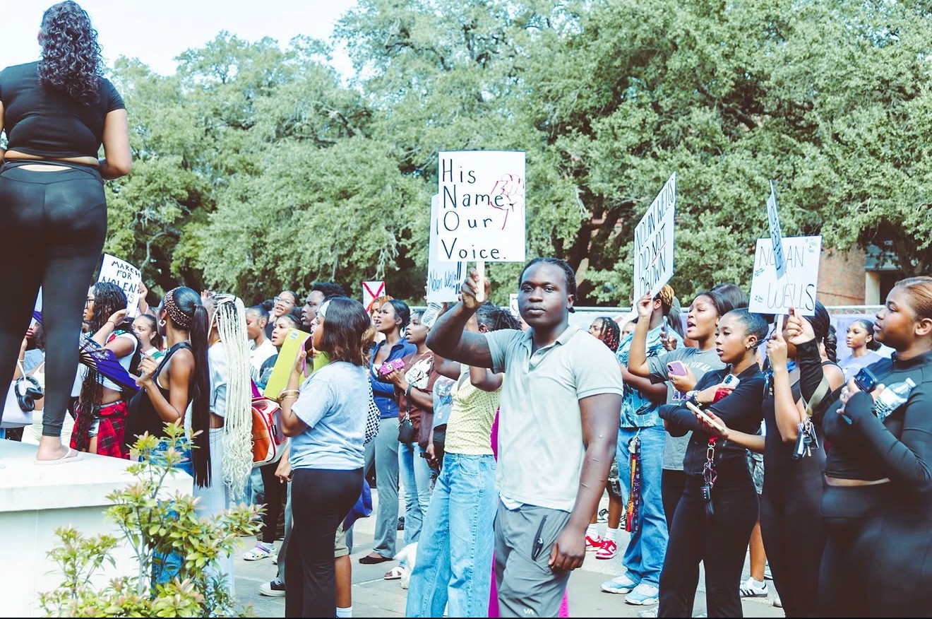 A participant holds a His Name Our Voice sign amid the rally crowd
